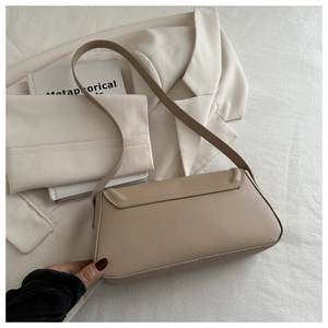 Close-up of minimalist beige leather underarm bag with flap and slim shoulder strap
