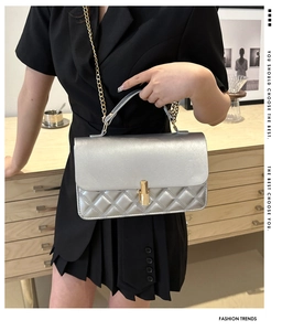 Silberne Stepptasche mit goldenem Verschluss und Kettenriemen am Modell