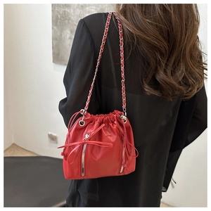 Detailed view of red bucket backpack with silver zippers and chain strap on a model
