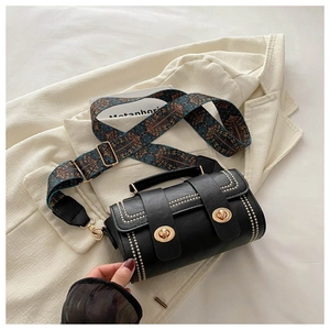 Detail of black cylindrical leather bag with gold rivets and ethnic print strap