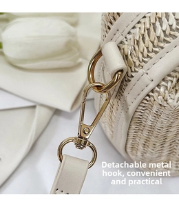 Close-up of detachable gold metal hooks on a stylish woven straw crossbody bag detail