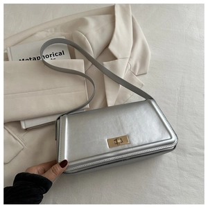 Detail of silver flap crossbody bag with golden twist lock on textured leather
