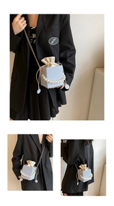Detail of light blue tweed bucket bag with large pearl handle and golden chain strap