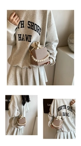 Detail of beige straw texture bag with pearl handle and metal chain strap