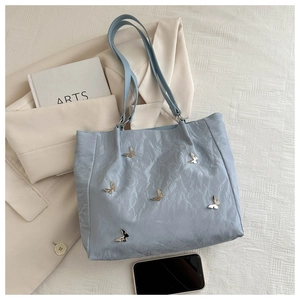 Close-up of light blue bucket bag featuring pleated texture and silver butterfly charms