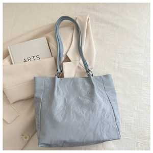 Macro shot of light blue bucket bag with pleated texture and stylish metal rings