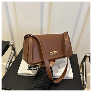 Detail of caramel leather shoulder bag showing the golden rectangular twist lock and texture
