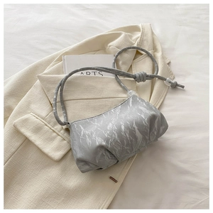 Detail of ruched silver marble pattern handbag on beige blazer with minimalist style