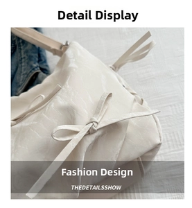 Close-up of cream shoulder bag with textured surface and decorative ribbon bow detail