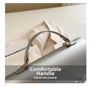 Details der silbergrauen Handtasche mit Ziernähten und Metallbeschlägen am Griff