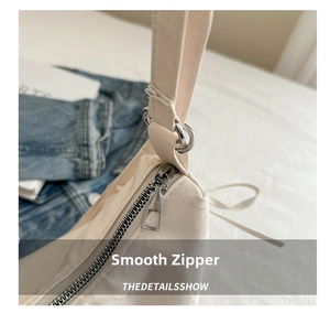 Macro view of smooth silver metal zipper and hardware on beige convertible tote bag