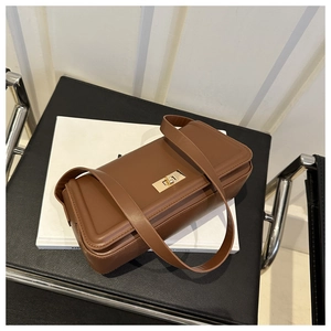 Detail view of large dark brown tote bag with gold square twist lock on a chair