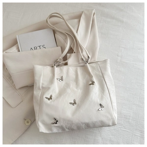 Close-up of pleated cream bucket bag featuring silver metallic butterfly accents