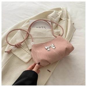 Detail of pink shoulder bag with silver bow ornament and textured moire fabric finish