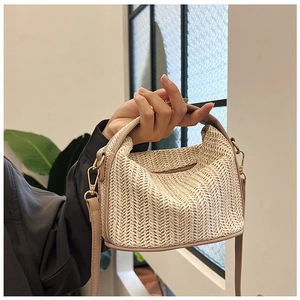 Detail of the herringbone straw weave and premium beige leather strap on this crossbody bag
