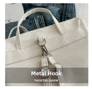 Détail des crochets en métal argenté et texture cuir verni blanc du sac à dos