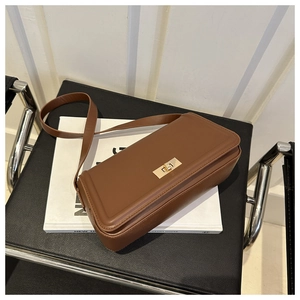 Detailed view of caramel brown leather handbag with gold metal clasp on white magazine