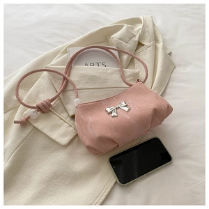 Detailed view of pink pleated handbag with silver butterfly knot and beaded strap
