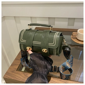 Macro detail of dark green vintage pillow bag with gold studs and embroidered strap