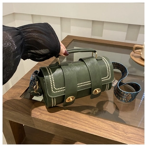 Detail of dark green leather pillow bag with gold rivets and bohemian strap