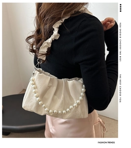 Dettaglio della borsa a mano increspata bianco panna con elegante catena di perle grandi
