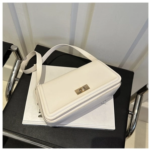 Detailed shot of a beige leather shoulder bag with a gold buckle on a modern chair