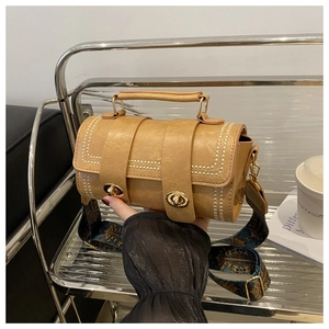 Detail view of retro brown cylinder bag with jacquard strap and gold buckle