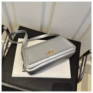 Detail shot of silver metallic crossbody bag with golden rotary lock on art books