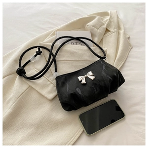 Detail view of black ruched shoulder bag with silver bow and adjustable cord strap