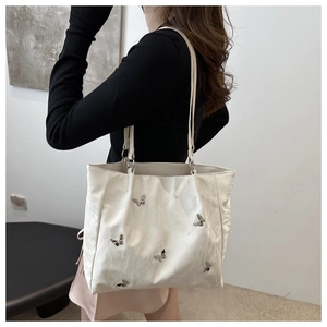 Detailed close-up of white bucket bag with silver butterfly charms and pleated texture