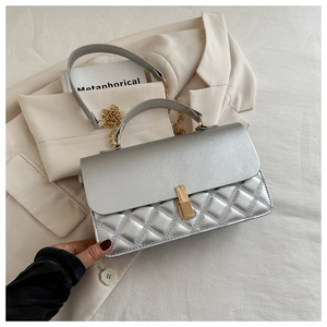 Detailaufnahme der silbernen Stepptasche mit goldener Schließe auf beigem Blazer