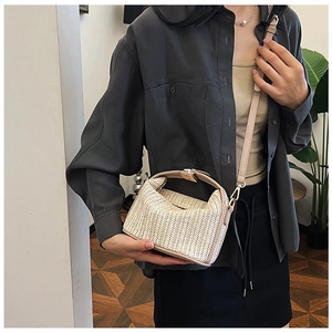 Detailed view of beige straw shoulder bag showing woven texture and gold hardware