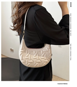 Detail view of cream crescent hobo bag with quilted texture and gold metal buckle