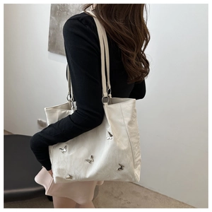Detail shot of white bucket bag with 3D silver butterflies and pleated PU leather finish