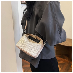 Detail of hand-woven straw shoulder bag with pink leather trim and gold metal buckle