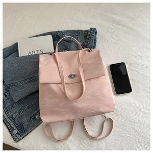 Detail of light pink backpack with marble texture and silver twist lock on white bedding