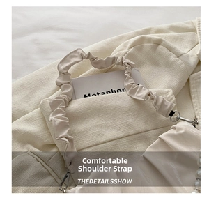 Detail of beige pleated cloud bag with elegant pearl strap and soft leather texture