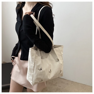 Detail view of a white bucket bag with silver metal butterfly accents on a female model