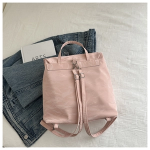 Detail of pink crinkled texture backpack with slim shoulder straps on denim background