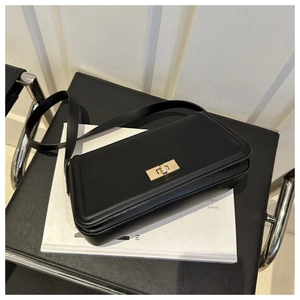 Detail shot of the golden rectangular twist lock on a black leather handbag