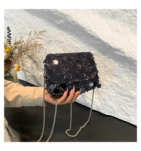 Detail of elegant black sequin crossbody bag with a slim silver metal chain strap