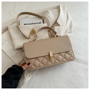 Detail der beigen Klapptasche mit Rautensteppung, goldenem Schloss und Kettenriemen