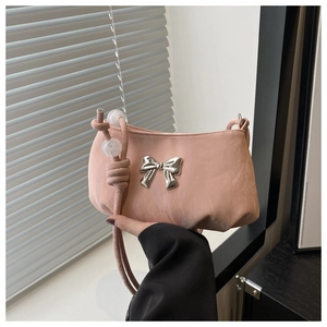 Detail of nude pink shoulder bag featuring silver bow accent and beaded knot strap