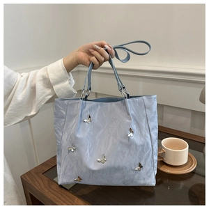 Close-up of light blue bucket bag with silver metal butterflies and pleated texture