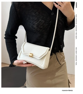 Detail of off-white leather crossbody bag with quilted edges and gold metal clasp closure