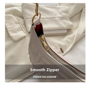 Macro shot of smooth gold metal zipper and red lining on off-white quilted handbag