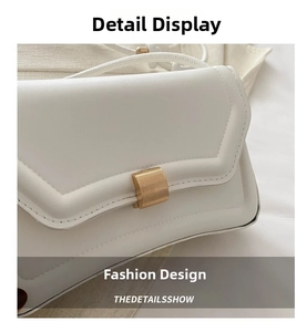 Detail of white leather shoulder bag featuring a gold textured buckle and fine stitching