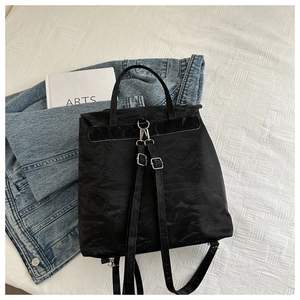 Detail of black wrinkled texture backpack with chain and silver hardware on white background