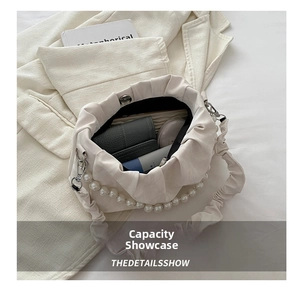 Detailed internal capacity view of white pleated handbag with pearls and daily essentials