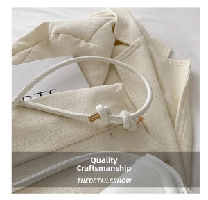 Detail of white leather saddle bag with cylindrical gold clasp and knotted strap
